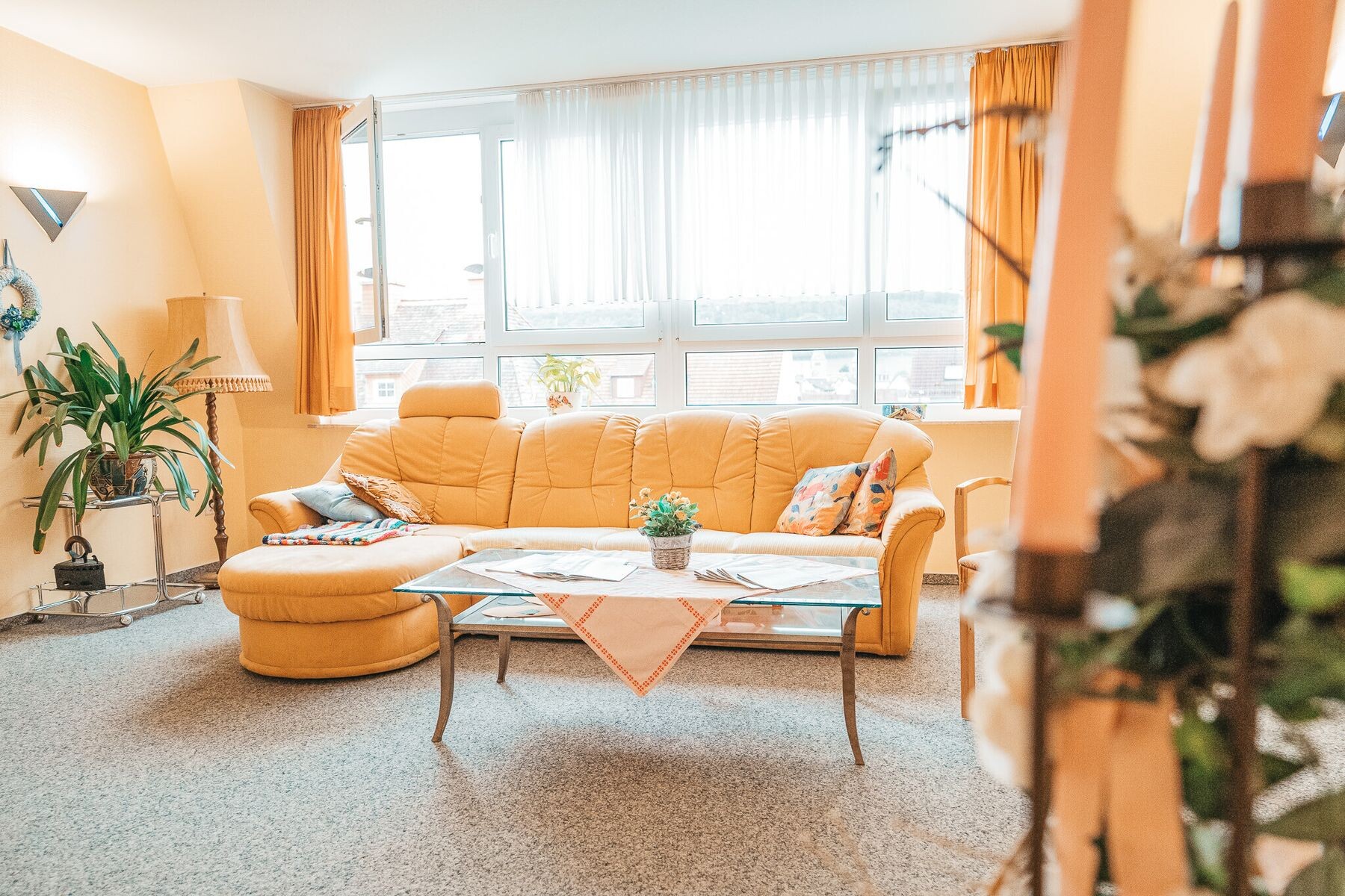 Heller Wohnbereich mit Sofa, Sessel und großem Fenstererker